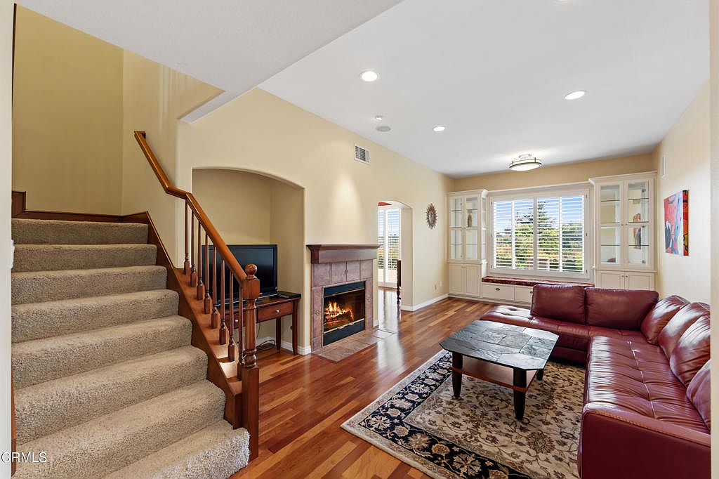 Living room with fireplace, rich hardwood floors, and built-in cabinetry